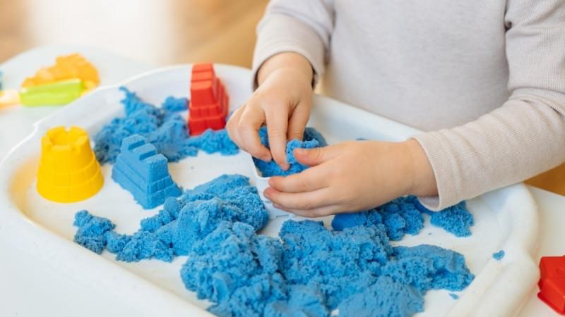 Montessori-Spielzeug - Kind spielt mit magnetischem Sand