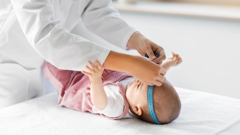 Arzt misst den Kopfumfang eines Kleinkindes